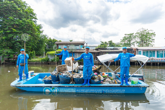 The boat crew stands on a boat full of river waste in the canal