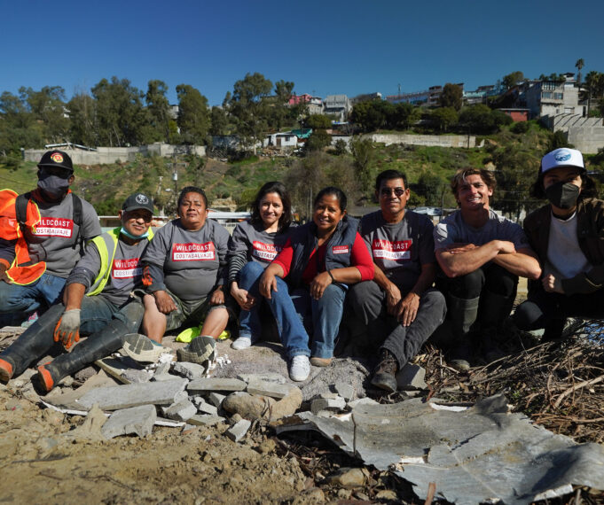 8 members of the WILDCOAST team sitting together and smiling at the camera onsite in Los Laureles Canyon.