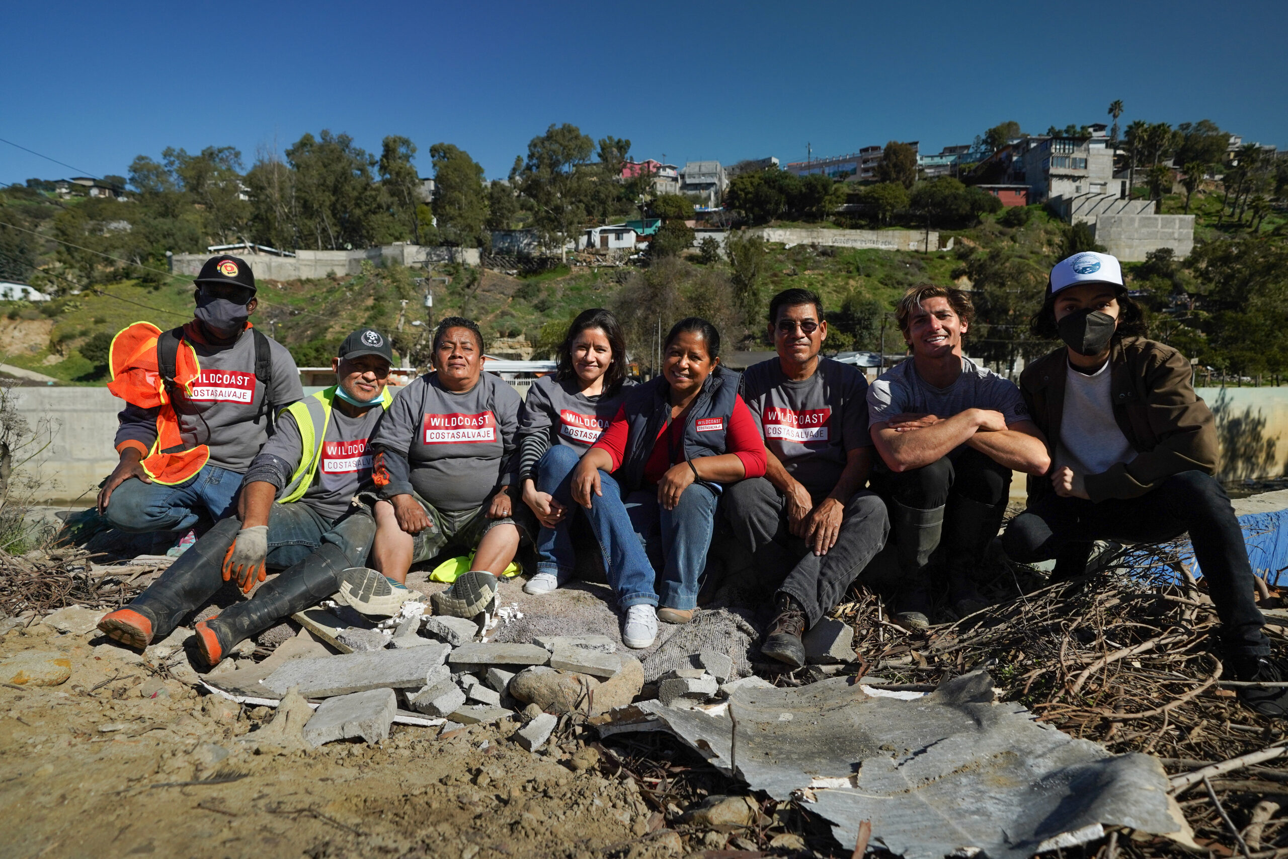 8 members of the WILDCOAST team sitting together and smiling at the camera onsite in Los Laureles Canyon.